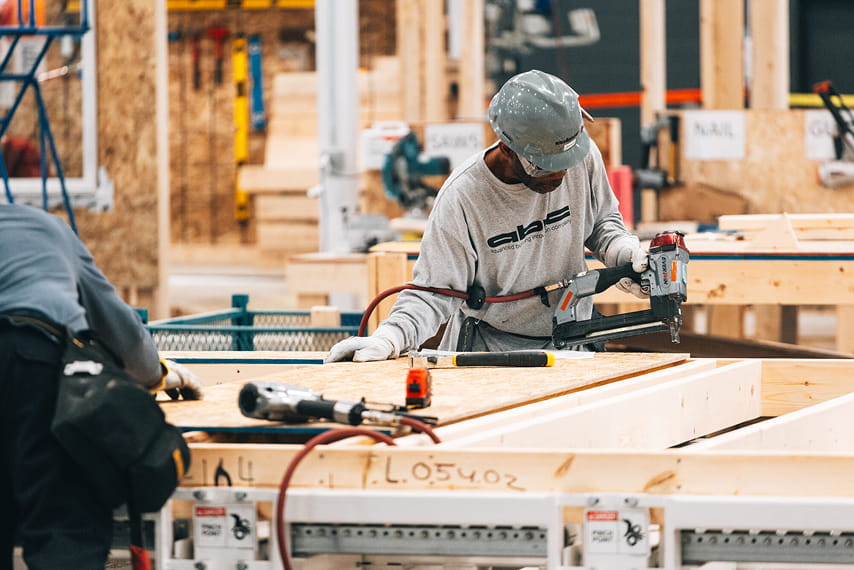 A man drilling sheets of wood together.